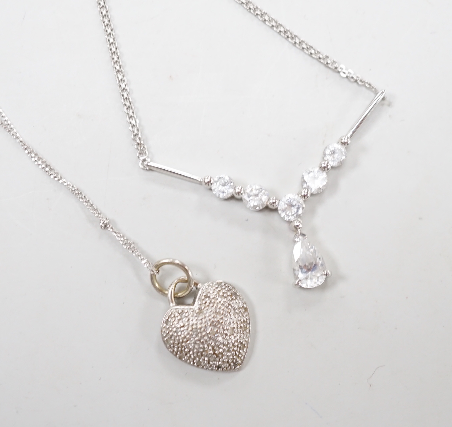 Two modern white metal (stamped 375) and gem set pendant necklaces, including a diamond chip set heart, longest 50cm